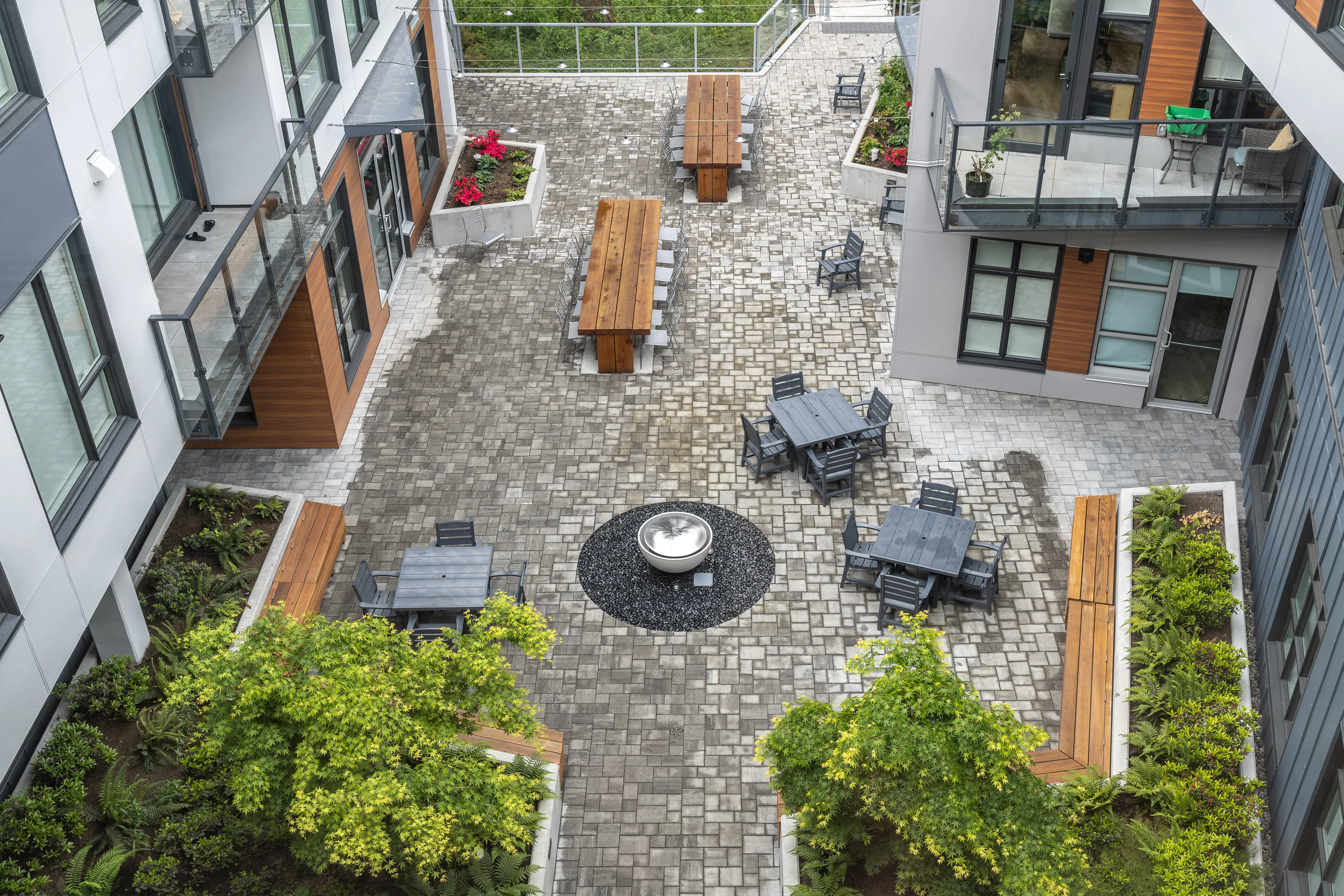 Aerial view of a courtyard with stone pavers, fire table and timber benches