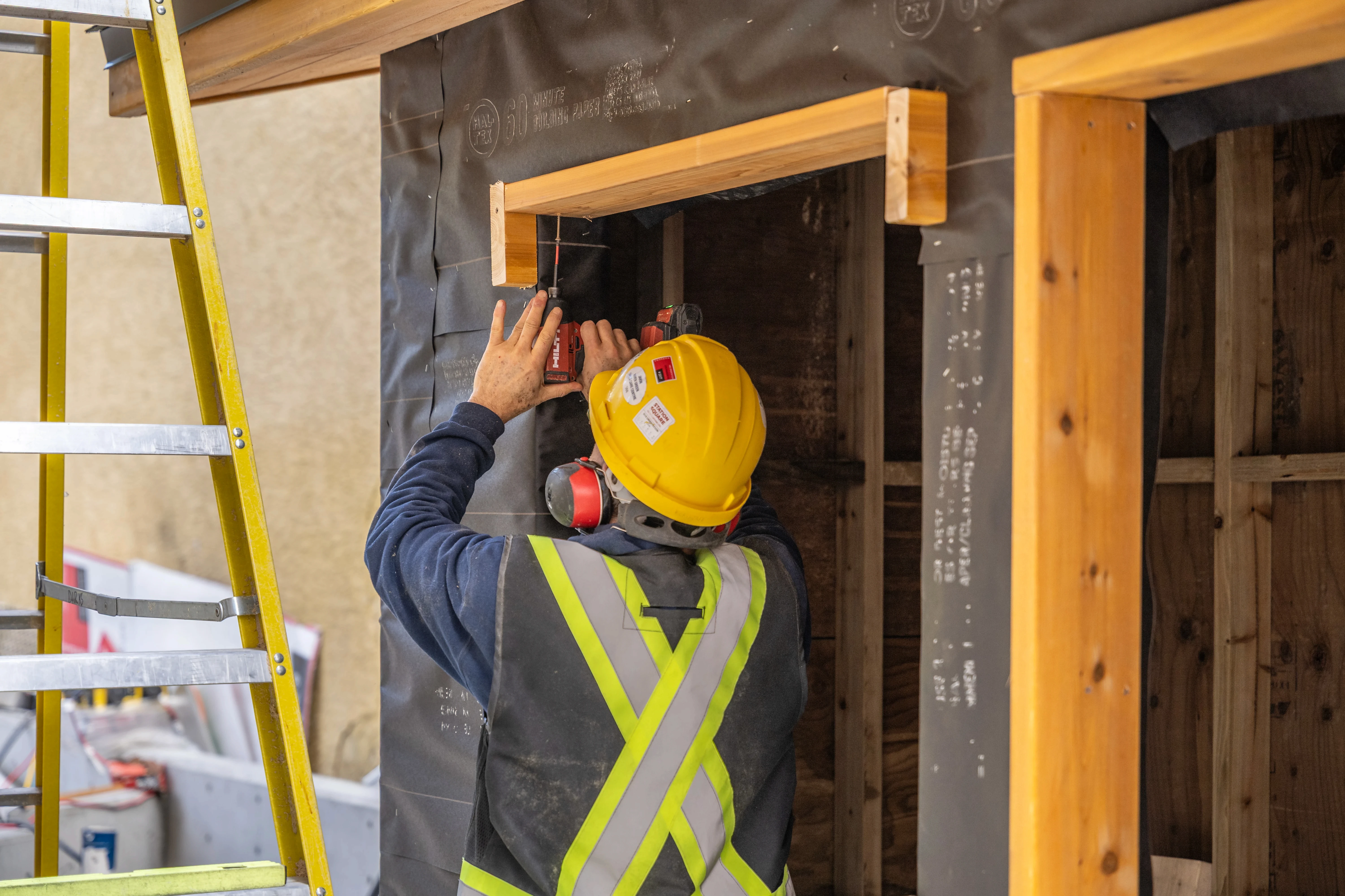 Worker in a hard hat and safety vest building timber framing
