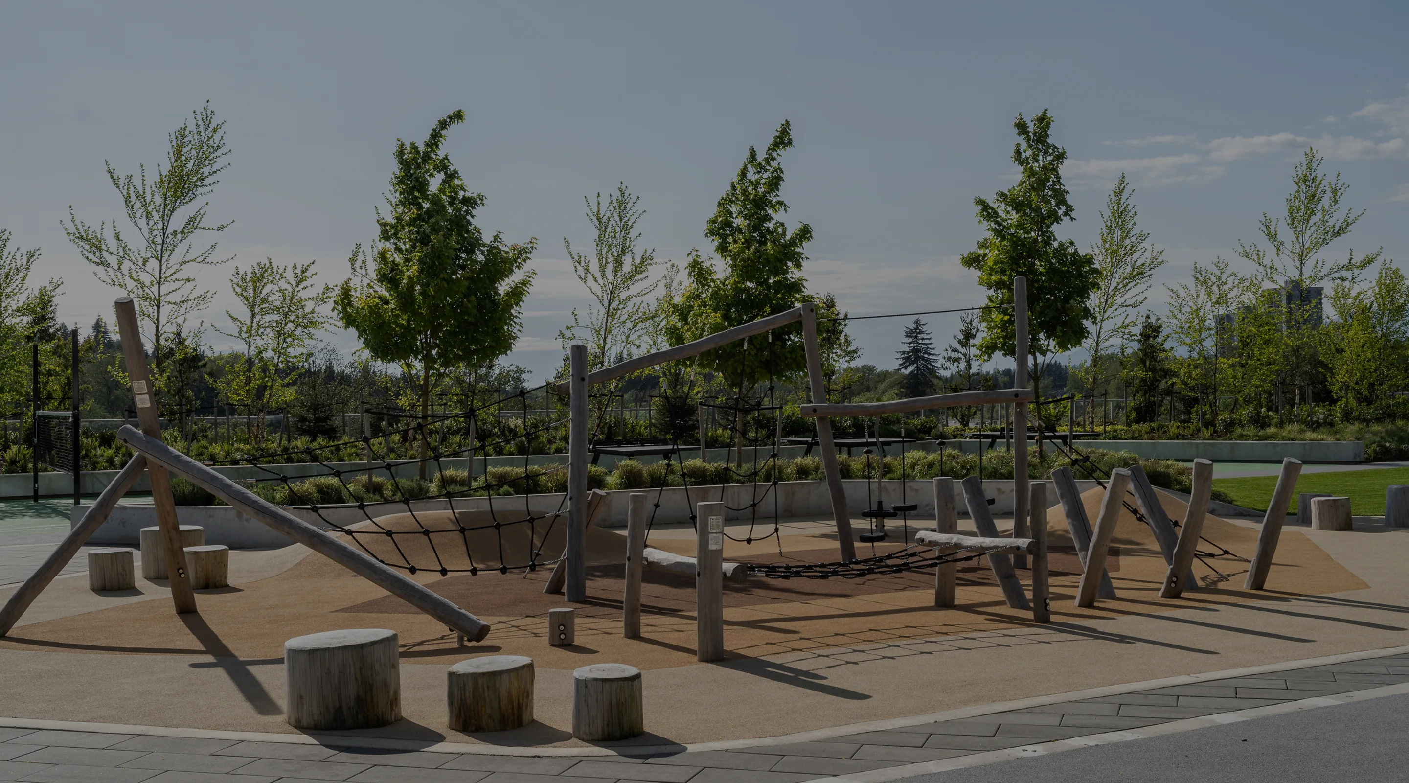 Timber play structure with log stumps and young trees in a playground