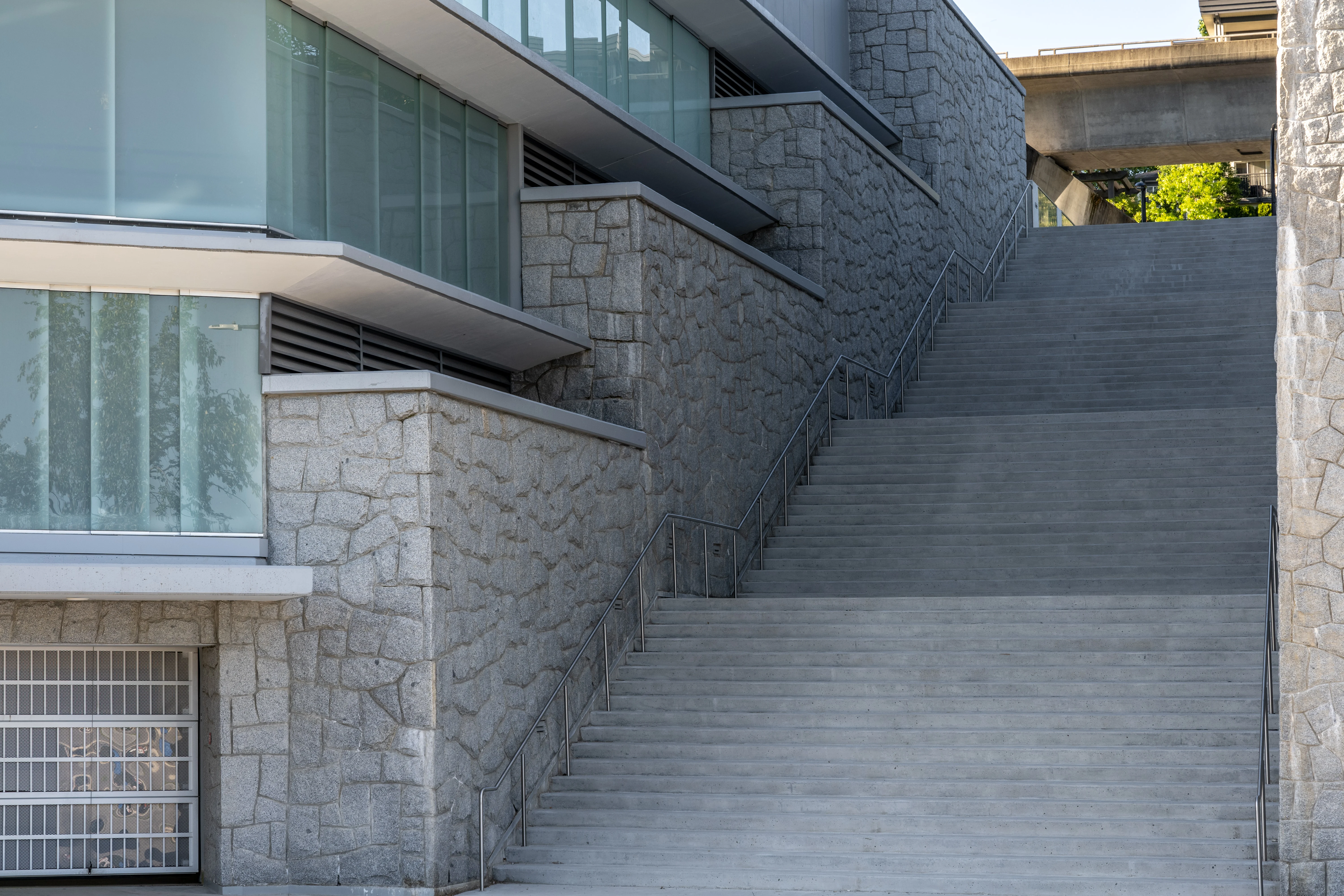 Stone-clad retaining walls and concrete stairs beside a building