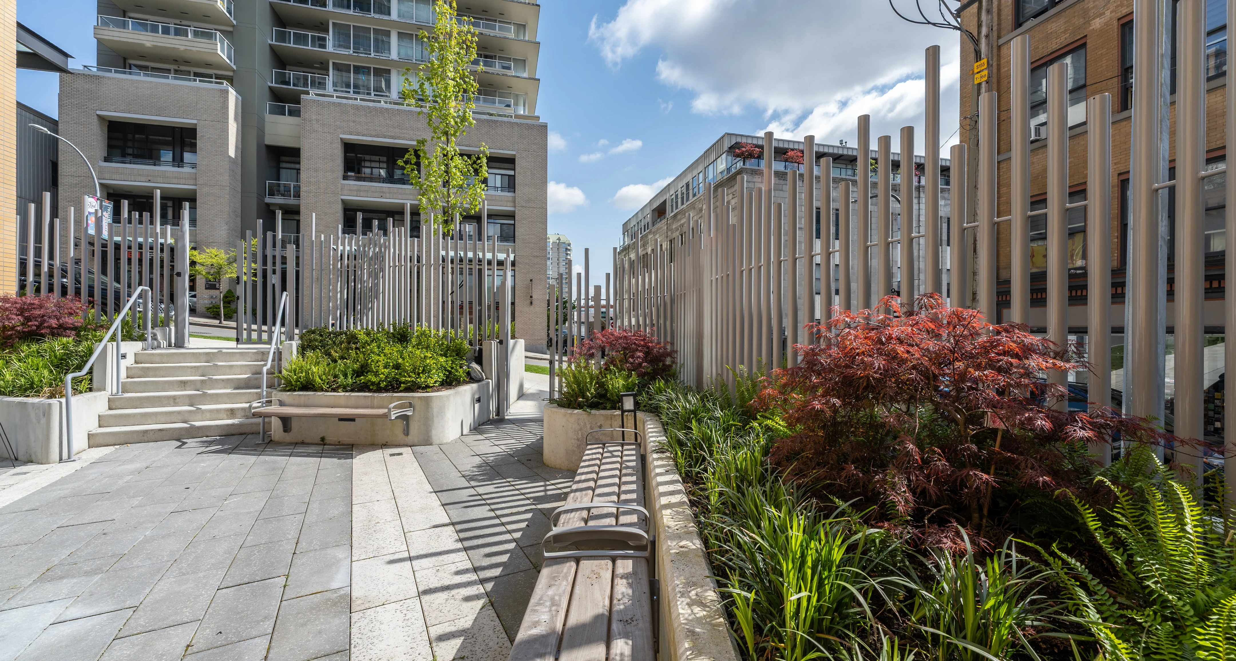 Planted walkway with timber benches between residential towers