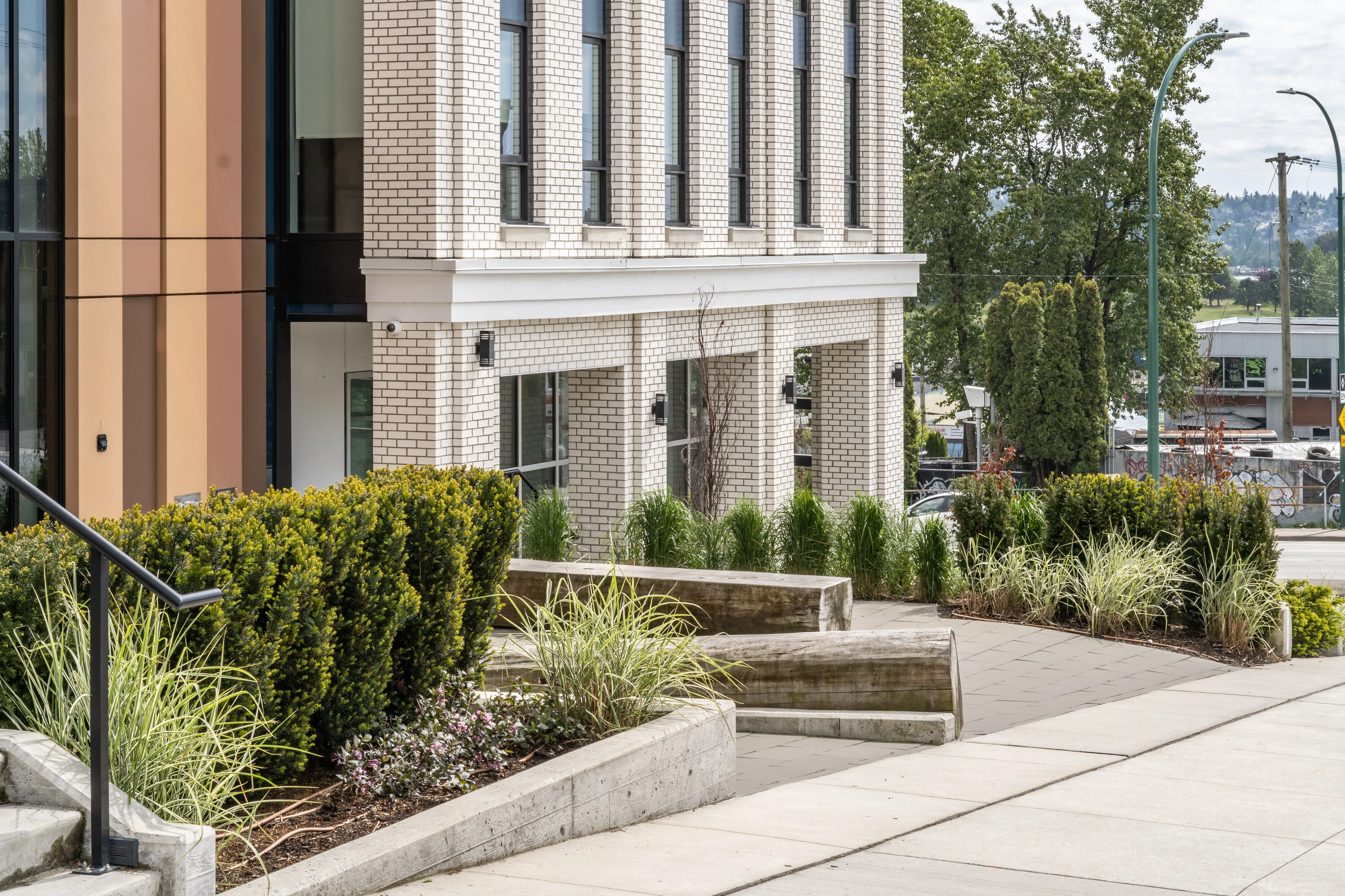Concrete steps with shrub and grass planting at a building corner at Loma