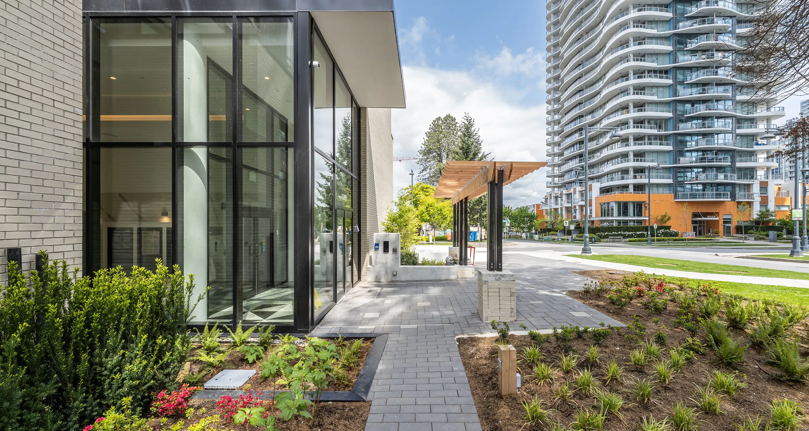 Paver walkway with planting beside a glass building entrance at Melrose