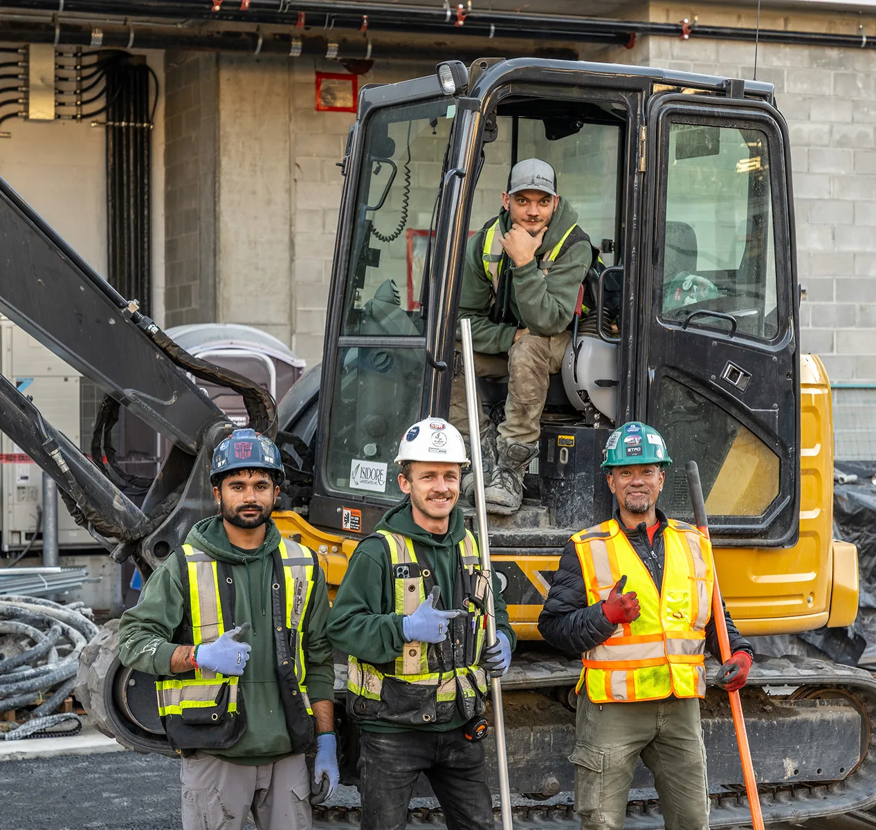 Landscape crew in safety gear posing with an excavator