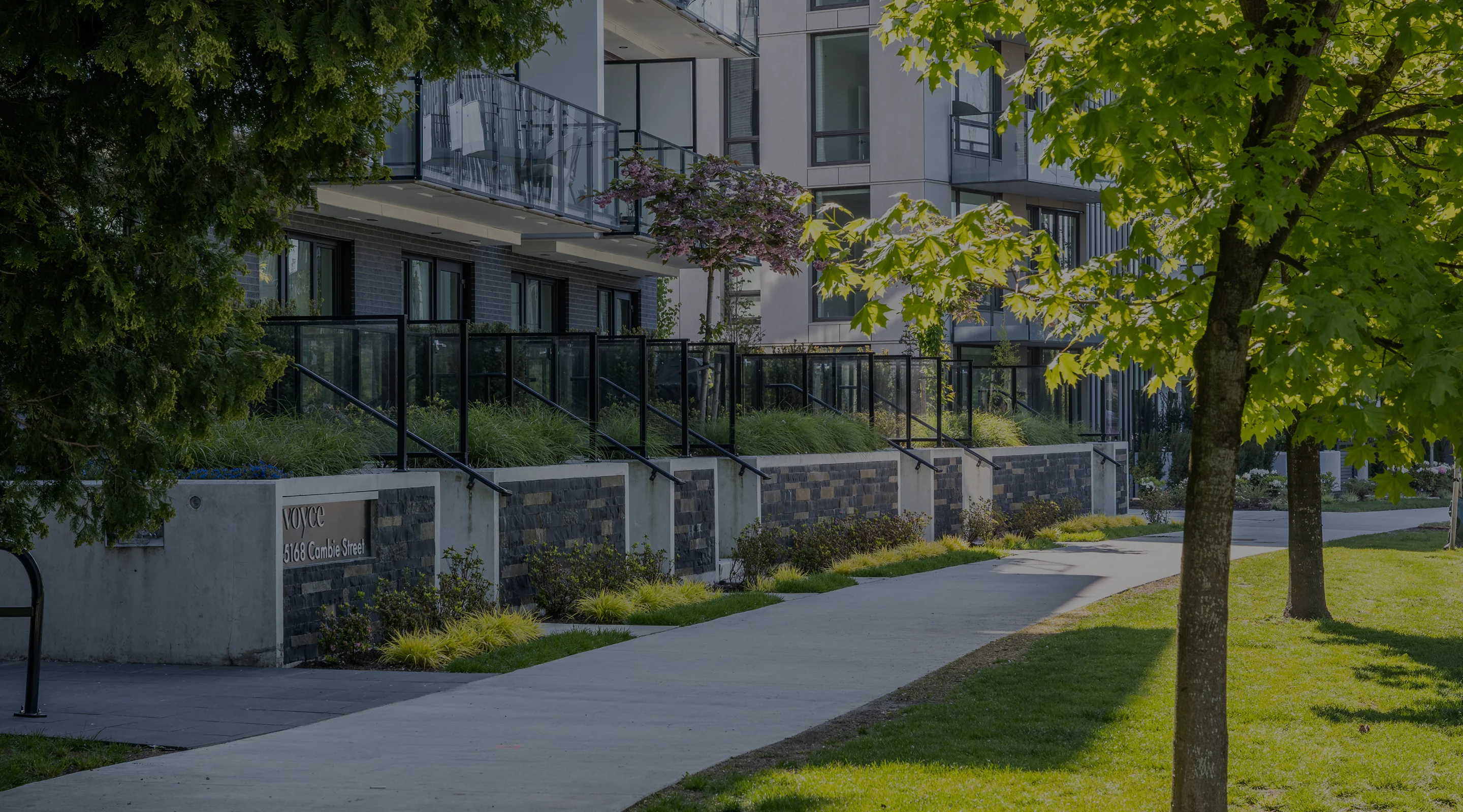 Lawn and walkway with trees in front of a low-rise residential building