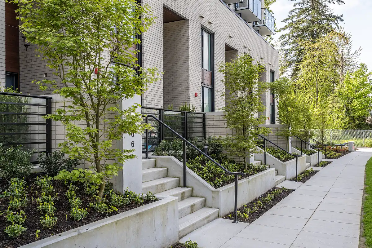 Townhome entry stairs with planted beds along a concrete sidewalk