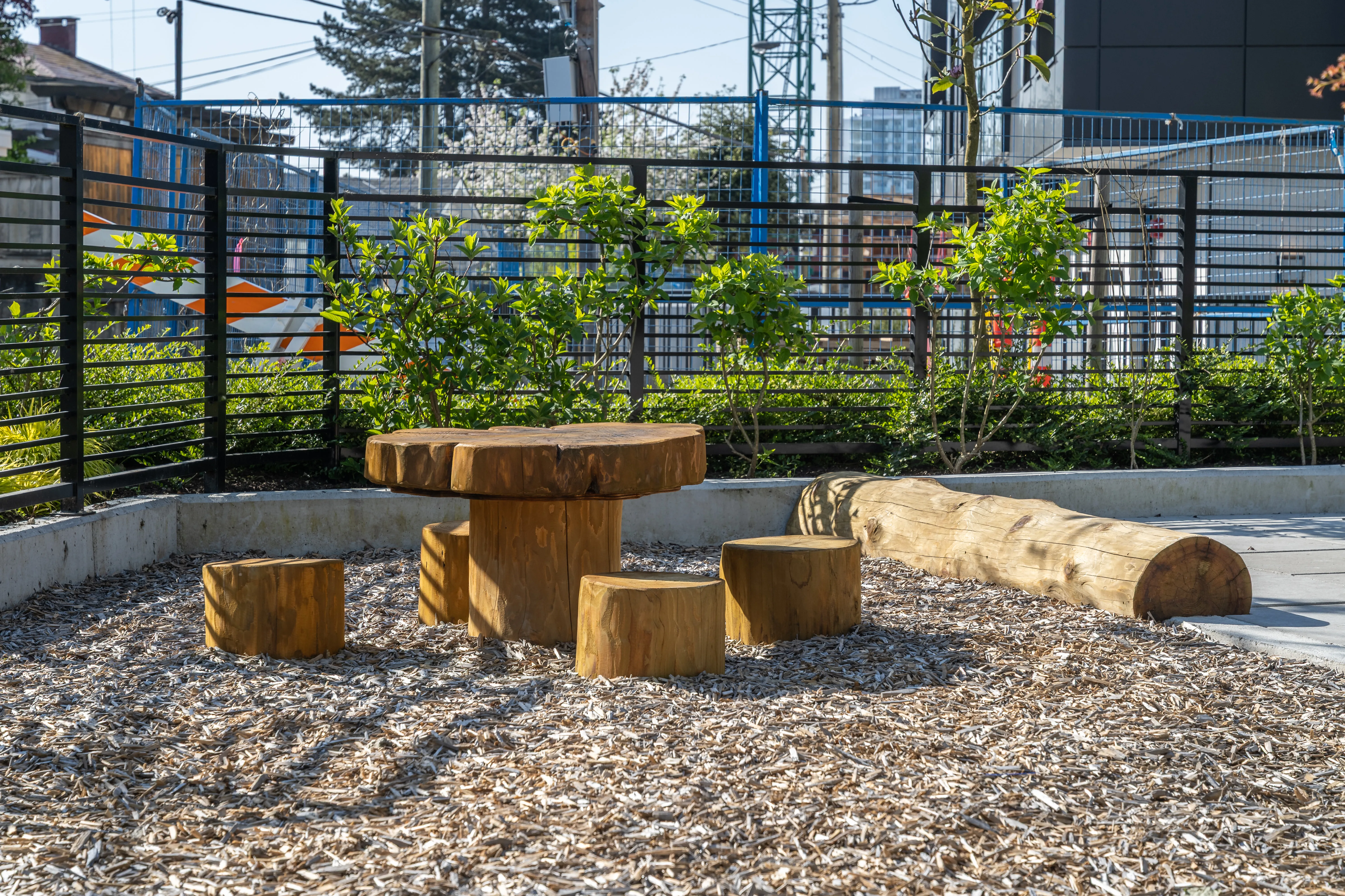 Timber log table and stumps on a wood chip play area at Voyce