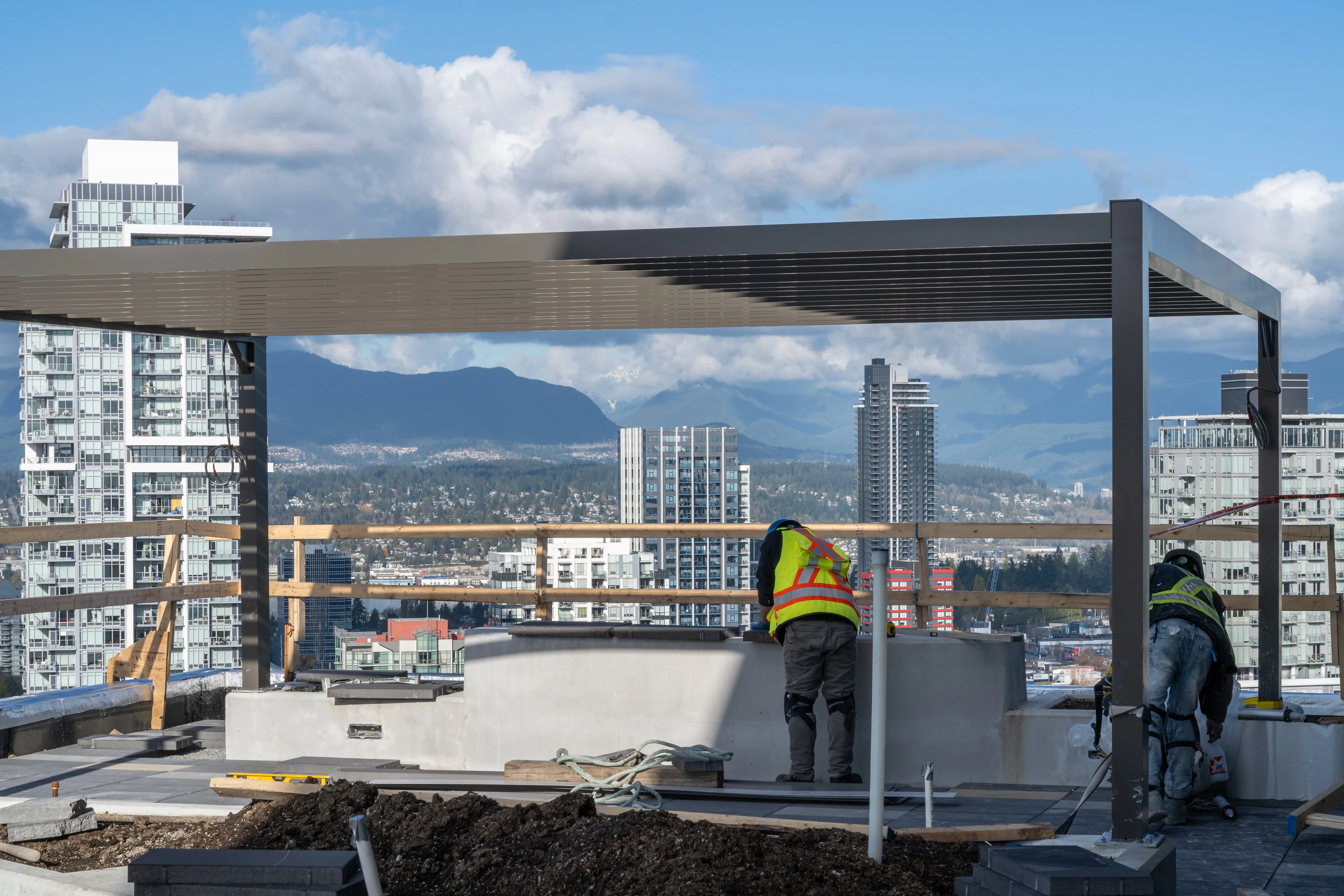 Crew building a rooftop pergola with the city skyline beyond